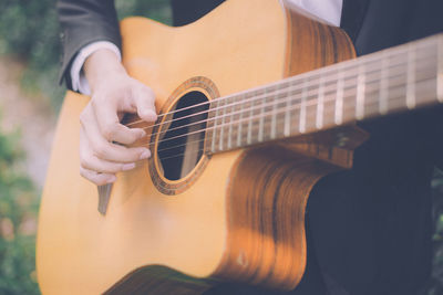 Midsection of man playing guitar