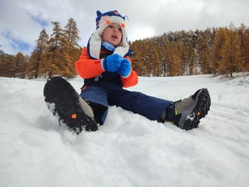 Portrait of boy playing with snow covered field