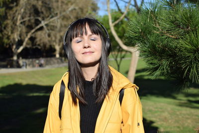 Portrait of young woman standing against trees