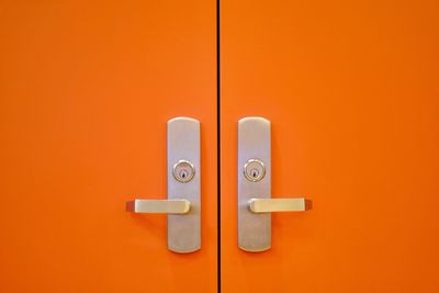 Close-up of closed door against orange wall