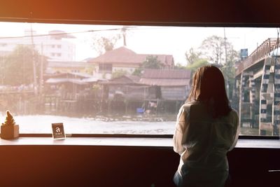 Rear view of woman looking through window