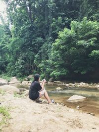 Man sitting by tree in forest