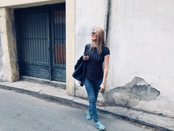 Full length of woman standing against wall