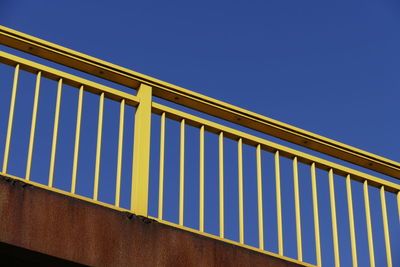 Low angle view of yellow bridge against clear blue sky