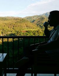 Man looking at camera while sitting on railing