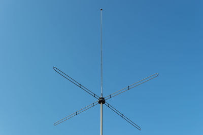 Low angle view of crane against clear blue sky
