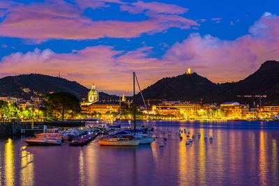 The city of como, in the evening, with the lakefront, the cathedral, and the surrounding mountains.