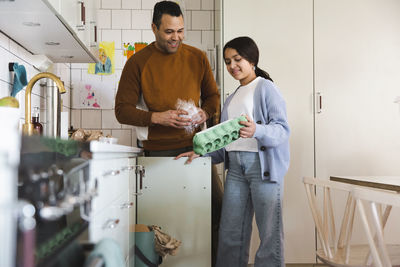 Father and daughter cleaning garbage in kitchen at home