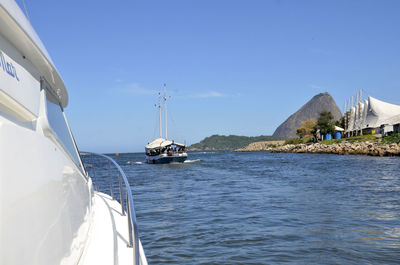 Boats sailing in sea against clear blue sky