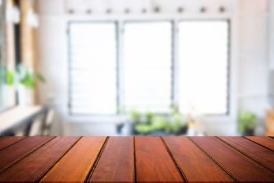 Close-up of wooden table against window at home