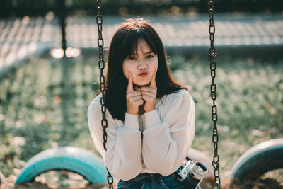 Portrait of woman sitting on swing at playground