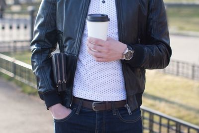 Midsection of man holding disposable cup