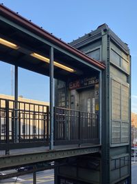 Low angle view of train against buildings against clear blue sky