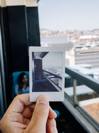 Midsection of person holding camera against sky