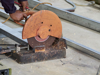 Cropped hands of man cutting metal with circular saw