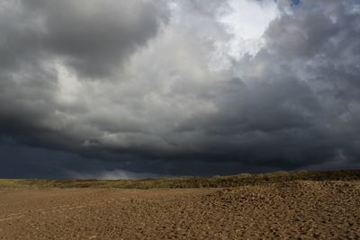 Scenic view of field against storm clouds