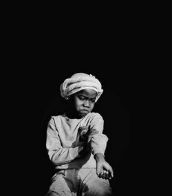 Portrait of woman standing against black background