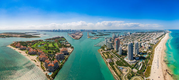 High angle view of sea and cityscape against blue sky