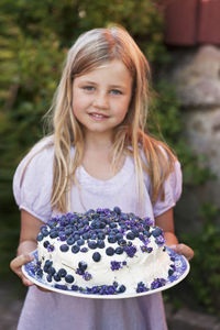 Blond hair girl holding blueberry cake