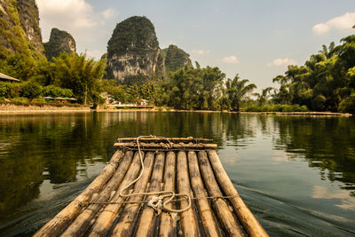 Scenic view of river against sky on wooden raft 