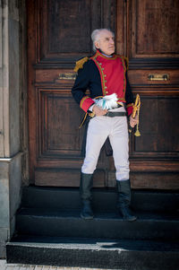 Full length portrait of senior man outside house