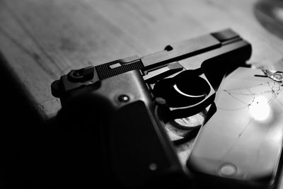 High angle view of handgun by mobile phone on table