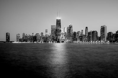 John hancock center by lake michigan against sky in city at night