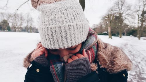 Close-up of woman covering face while standing outdoors during winter