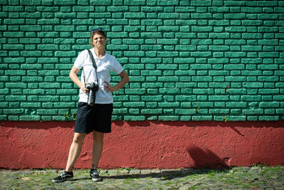 Full length of man standing against brick wall