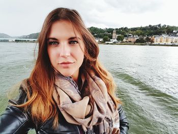 Portrait of beautiful young woman against river