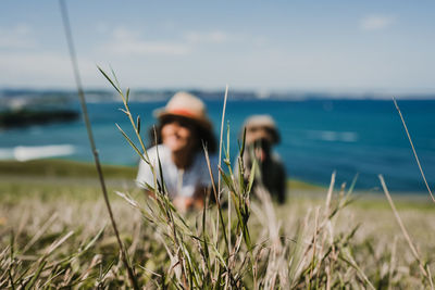 Happy woman with dog on field against sea