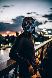 Portrait of man in illuminated bus against sky at night