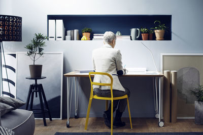 Rear view of woman working at table in creative office