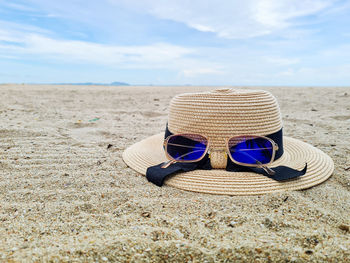 Sunglasses on sand at beach against sky
