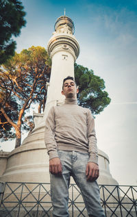 Low angle portrait of young man standing against tower