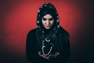 Young woman standing against red background