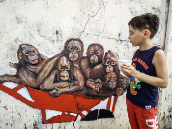 Full length of boy with monkey standing outdoors