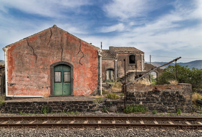 Old railroad tracks by building against sky