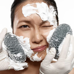 Close-up of young woman applying cream with equipment on face