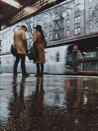 Friends standing on railroad station platform during rainy season