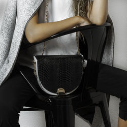 Midsection of woman with purse sitting on chair 