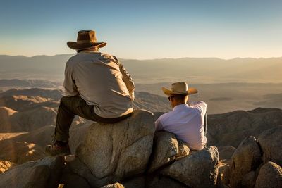 People sitting on landscape against sky