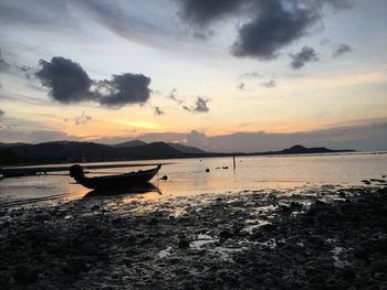 Boat moored on beach against sky during sunset