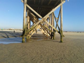 Below view of pier on shore at beach against sky