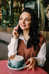 Portrait of a smiling young woman sitting at table
