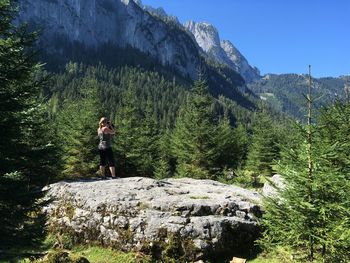 Woman standing on rock photographing scenery