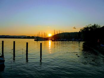 Silhouette of wooden post in sea against sky during sunset