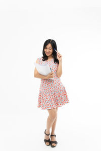 Full length portrait of woman standing against white background