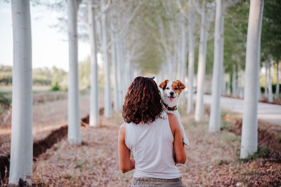 Rear view of woman standing against trees