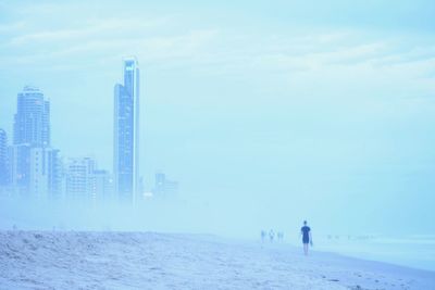 Rear view of man walking at beach in foggy weather